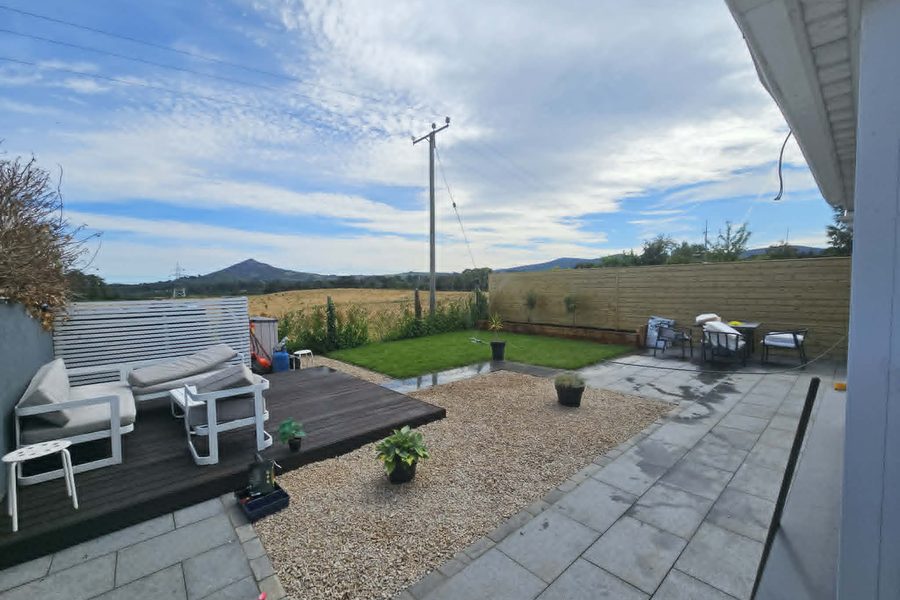 The same garden after: granite paving, composite decking, clean gravel and a new lawn