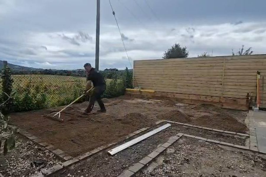 Maciek raking the ground level during the rebuild, the Great Sugar Loaf behind
