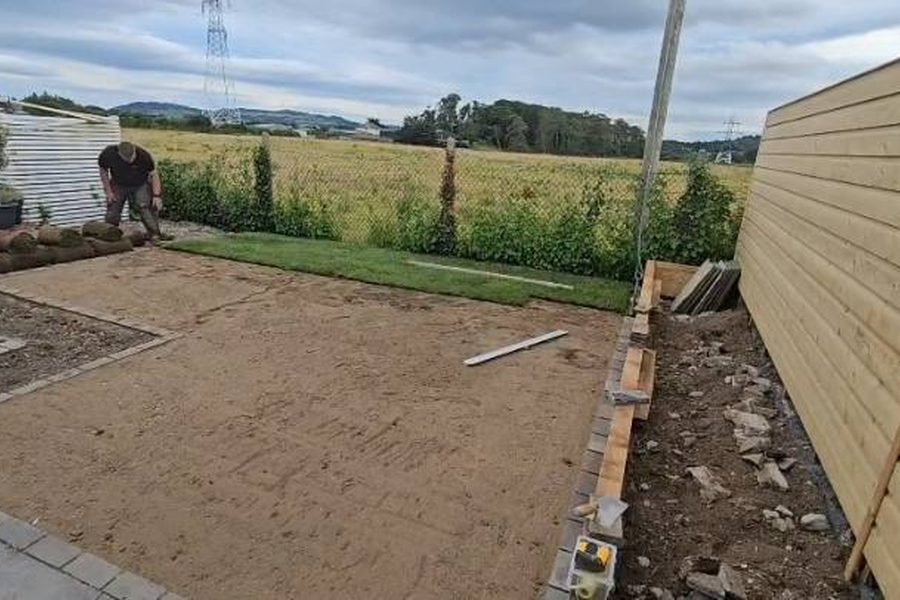 Rolls of turf being laid over the prepared ground